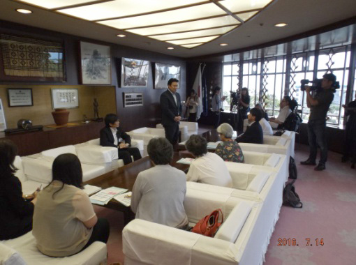 市長室で市長に報告する委員会メンバーたちの写真