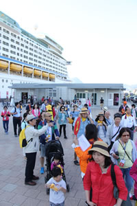 港で、巨大なクルーズ船から降り立ったばかりの観光客たちの様子。/