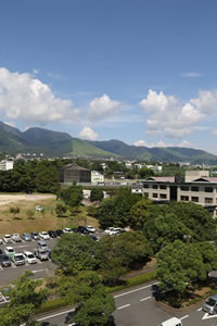 青空と山々を背景に、別府市役所を駐車場側から離れて写した写真。