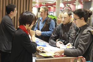 別府駅のインフォメーションカウンターで、スタッフに何かを尋ねている外国人観光客たちの写真